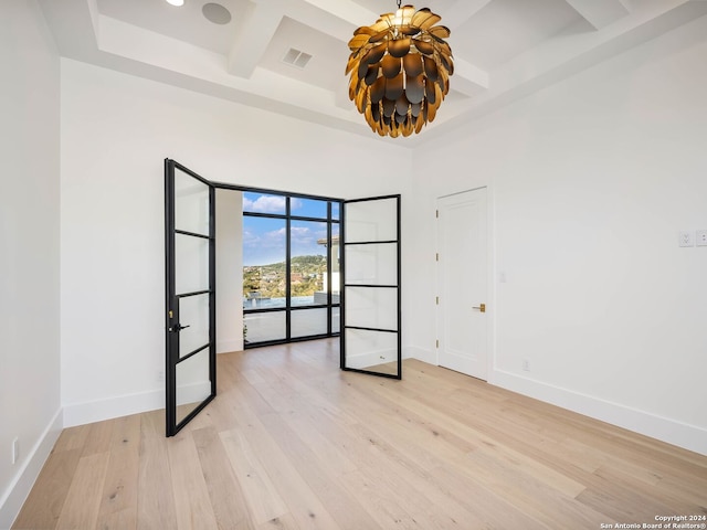 empty room featuring beam ceiling, light wood-type flooring, and coffered ceiling