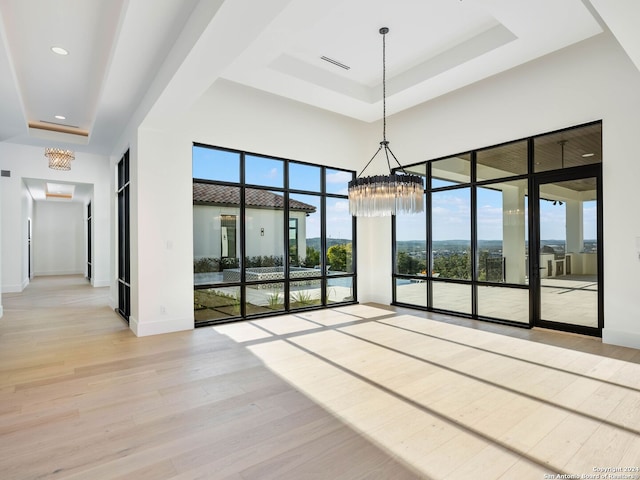 interior space with an inviting chandelier, a tray ceiling, and light hardwood / wood-style flooring