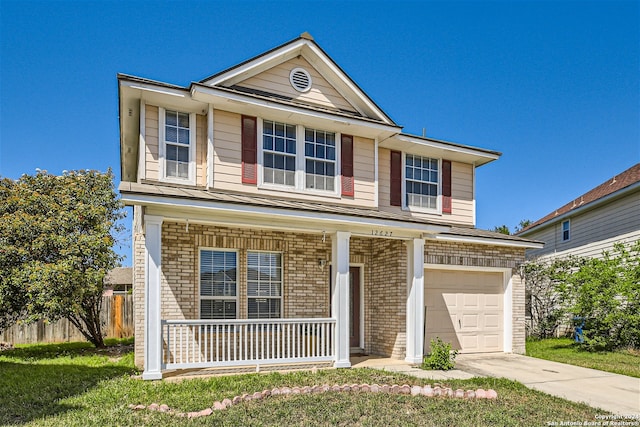 front facade featuring covered porch, a garage, and a front yard