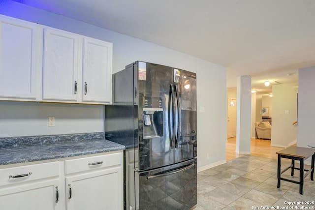 kitchen featuring white cabinets, black fridge with ice dispenser, and light tile patterned flooring