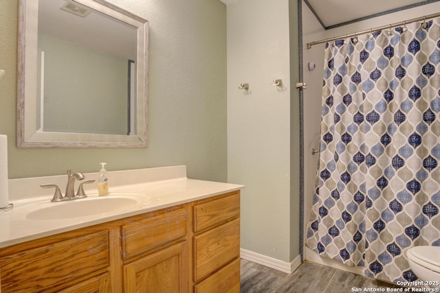 bathroom with a shower with shower curtain, hardwood / wood-style floors, vanity, and toilet