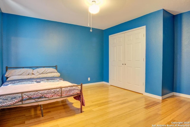 bedroom with wood-type flooring, a closet, and ceiling fan