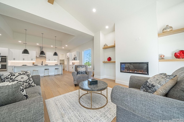 living room featuring light wood-type flooring, sink, and vaulted ceiling