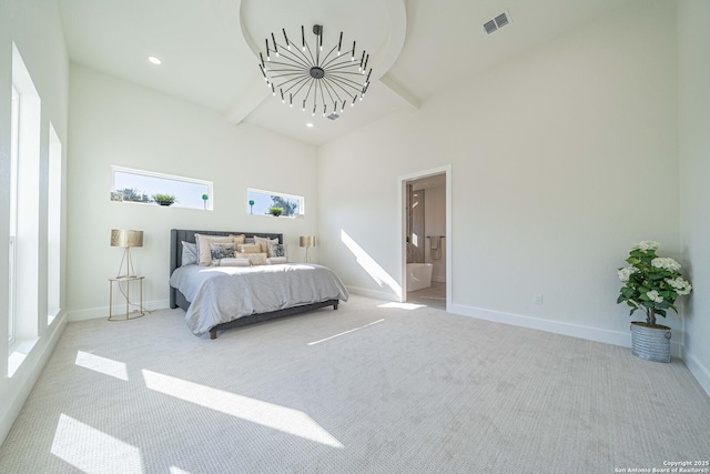 bedroom with connected bathroom, a chandelier, a towering ceiling, and light colored carpet