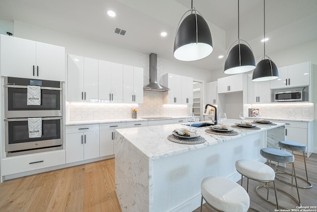 kitchen featuring white cabinets, pendant lighting, wall chimney exhaust hood, and sink