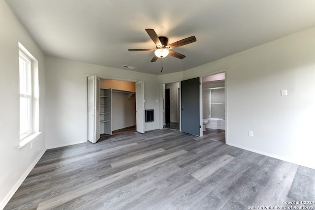 unfurnished bedroom with multiple windows, ceiling fan, hardwood / wood-style floors, and ensuite bathroom