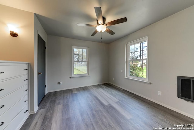 unfurnished bedroom with ceiling fan, dark hardwood / wood-style floors, and heating unit