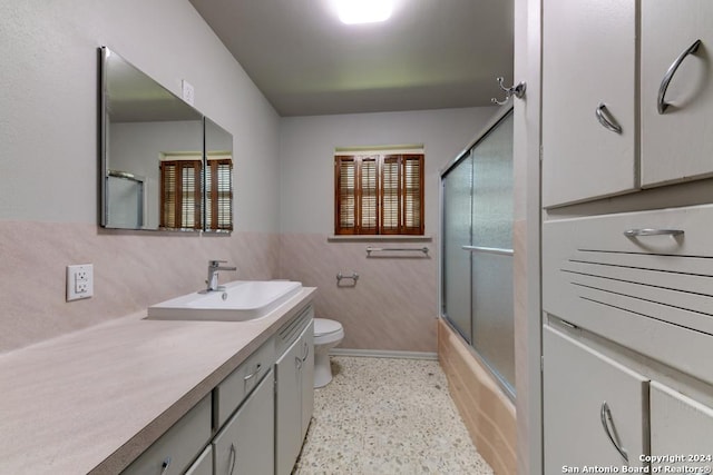 full bathroom featuring vanity, toilet, enclosed tub / shower combo, and tile walls