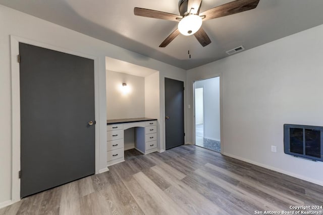 unfurnished bedroom with heating unit, ceiling fan, and light wood-type flooring