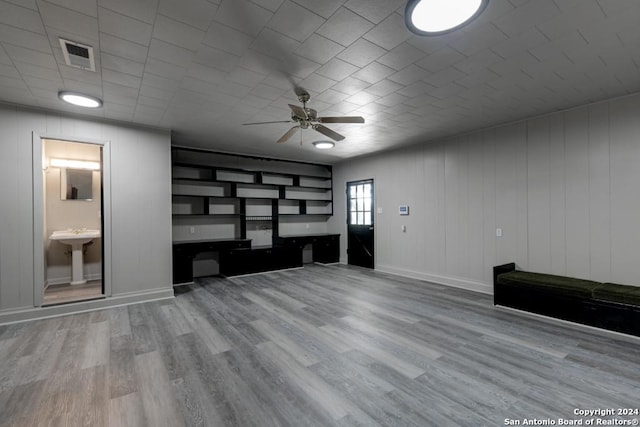 unfurnished living room with wood-type flooring, ceiling fan, and sink