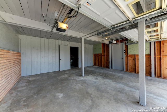 garage with a garage door opener and wooden walls