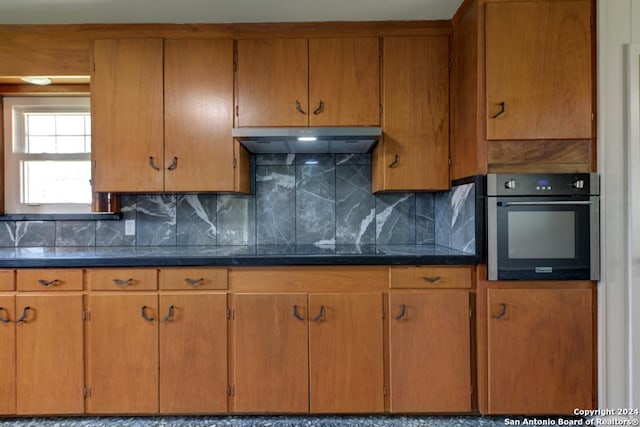 kitchen featuring oven, decorative backsplash, and black cooktop