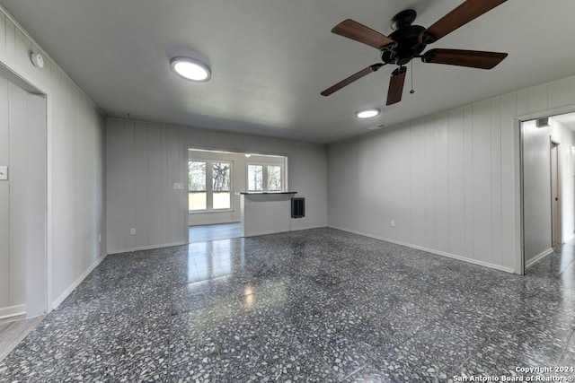 unfurnished living room with ceiling fan and wooden walls