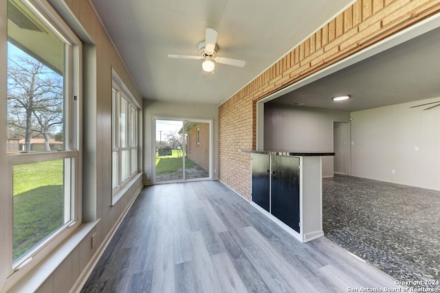 unfurnished sunroom featuring ceiling fan and a healthy amount of sunlight