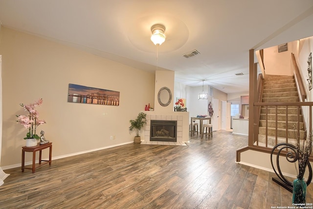 living room with a tile fireplace and hardwood / wood-style flooring