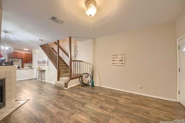 unfurnished living room with wood-type flooring and a tiled fireplace