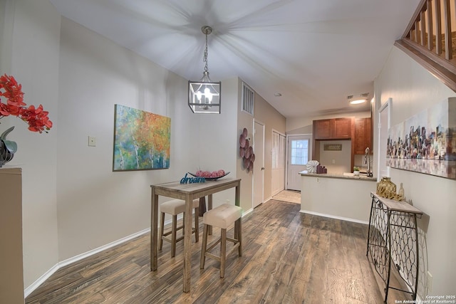 dining area with sink, dark wood-type flooring, and an inviting chandelier