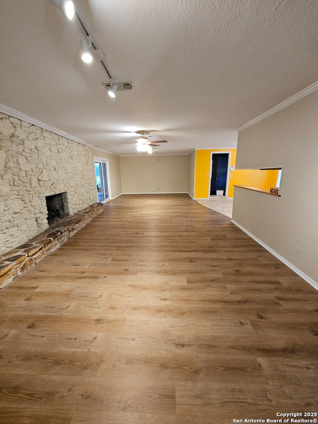 basement with hardwood / wood-style floors, track lighting, ornamental molding, a fireplace, and a textured ceiling