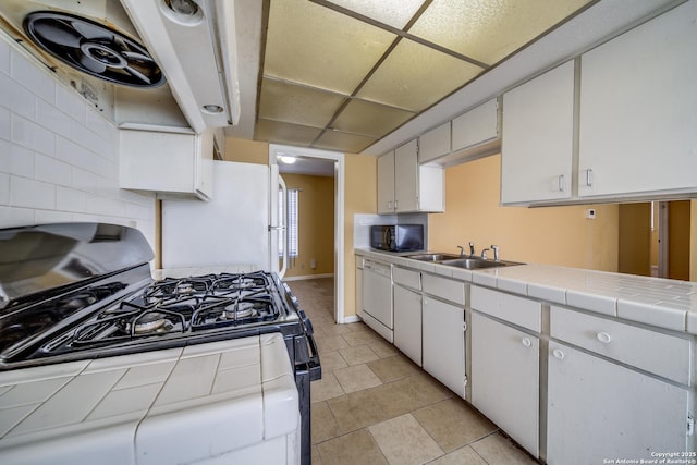 kitchen featuring white cabinetry, sink, tile countertops, white appliances, and decorative backsplash