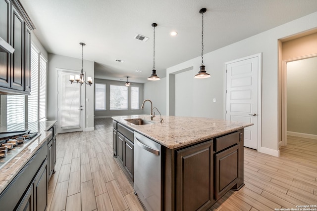 kitchen with stainless steel dishwasher, dark brown cabinetry, sink, hanging light fixtures, and an island with sink