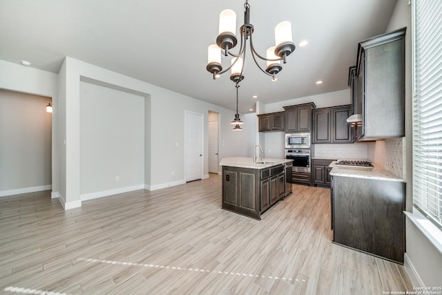 kitchen with sink, hanging light fixtures, an inviting chandelier, an island with sink, and appliances with stainless steel finishes