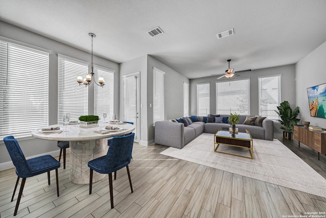 dining area featuring ceiling fan with notable chandelier, plenty of natural light, and a textured ceiling