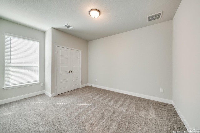 unfurnished bedroom with multiple windows, a closet, and light colored carpet