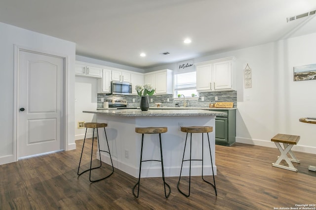 kitchen with a kitchen bar, a center island, white cabinets, and stainless steel appliances