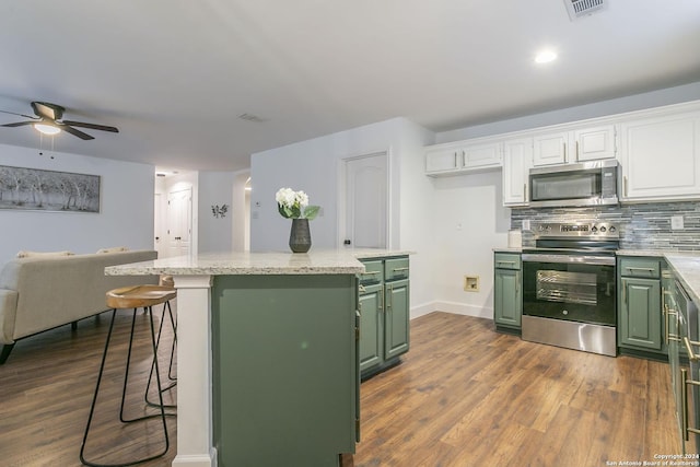 kitchen with backsplash, a breakfast bar, stainless steel appliances, green cabinetry, and white cabinets