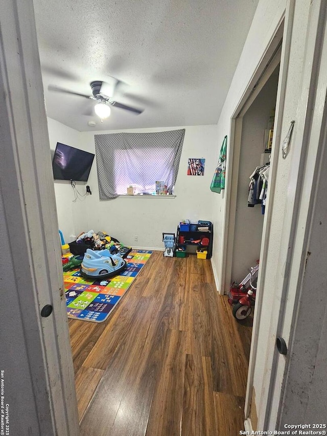 bedroom featuring ceiling fan, hardwood / wood-style floors, and a textured ceiling