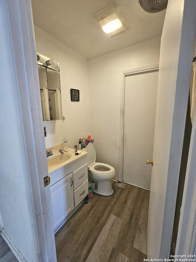 bathroom with wood-type flooring, vanity, and toilet