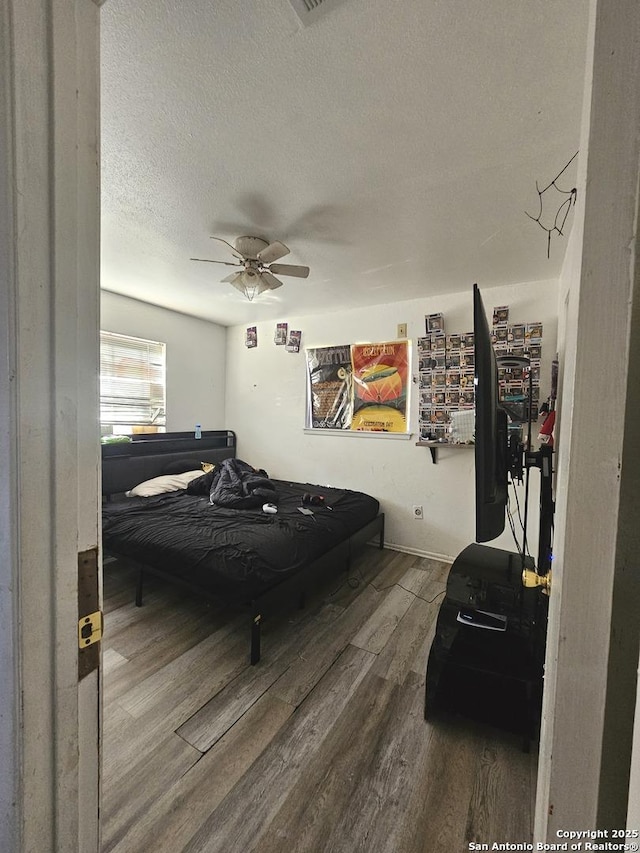 bedroom with ceiling fan, wood-type flooring, and a textured ceiling