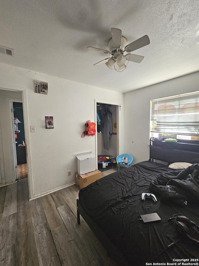 bedroom featuring a textured ceiling, dark hardwood / wood-style flooring, a closet, and ceiling fan