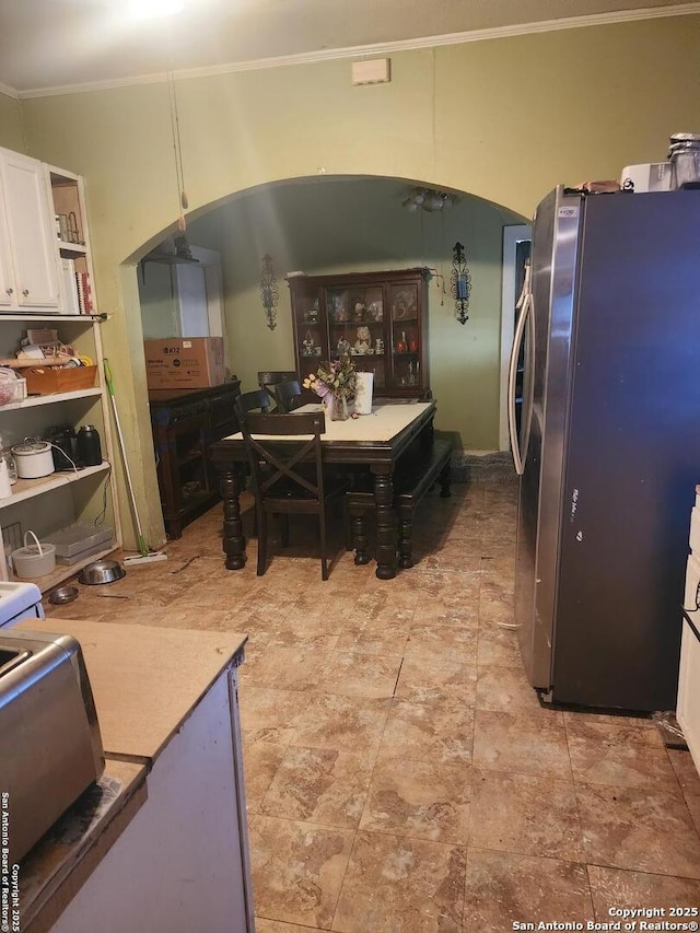 kitchen with decorative light fixtures, white cabinetry, stainless steel refrigerator, and ornamental molding