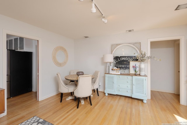 dining area with rail lighting and light hardwood / wood-style floors