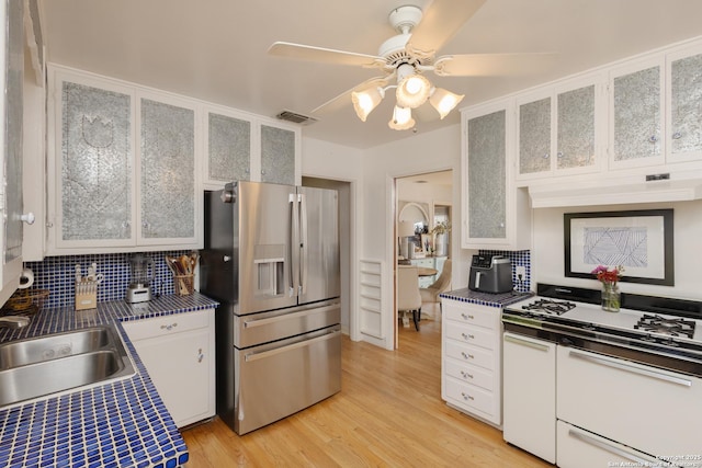 kitchen with white cabinets, white range oven, stainless steel fridge with ice dispenser, and sink