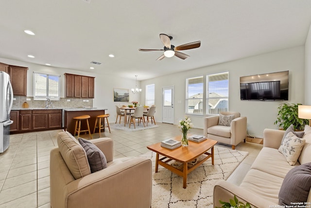 living room featuring light tile patterned flooring, plenty of natural light, and ceiling fan with notable chandelier