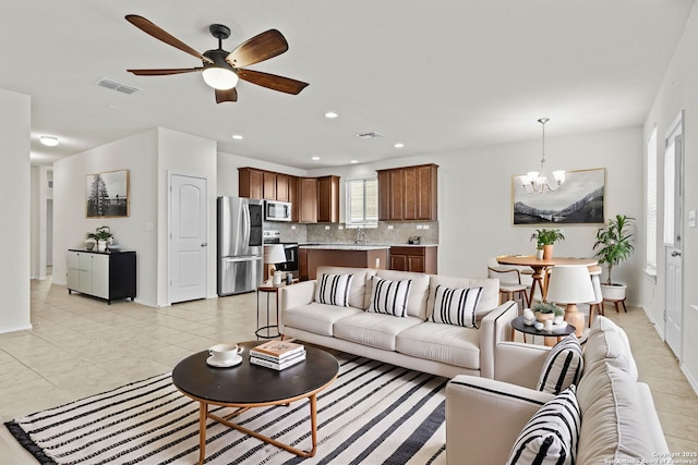 living room with sink, ceiling fan with notable chandelier, and light tile patterned floors