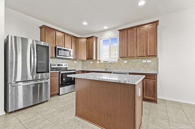 kitchen featuring decorative backsplash, light stone countertops, stainless steel appliances, and a kitchen island