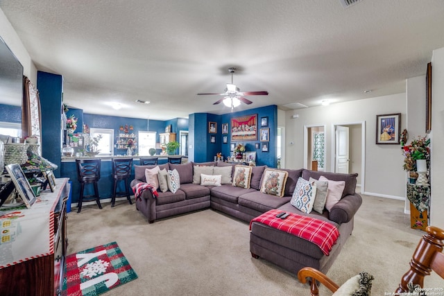 carpeted living room with a textured ceiling, ceiling fan, and indoor bar