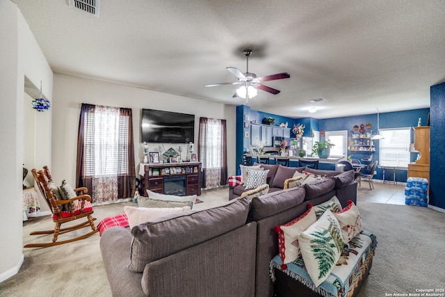 carpeted living room featuring ceiling fan and a textured ceiling