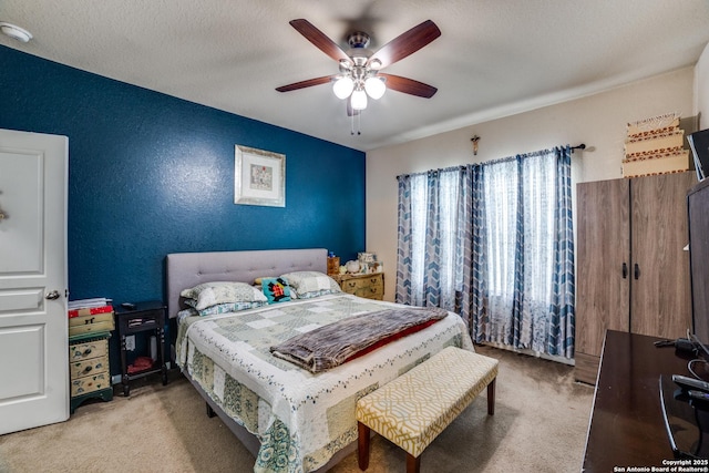 carpeted bedroom with ceiling fan and a textured ceiling