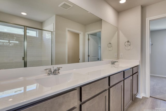 bathroom with hardwood / wood-style floors, vanity, and a shower with shower door