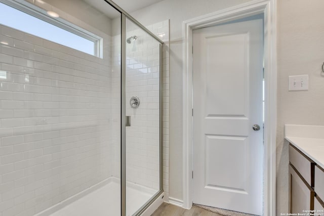 bathroom with hardwood / wood-style flooring, vanity, and walk in shower