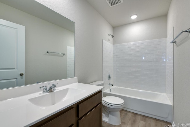 full bathroom with vanity, hardwood / wood-style floors, tiled shower / bath combo, and toilet