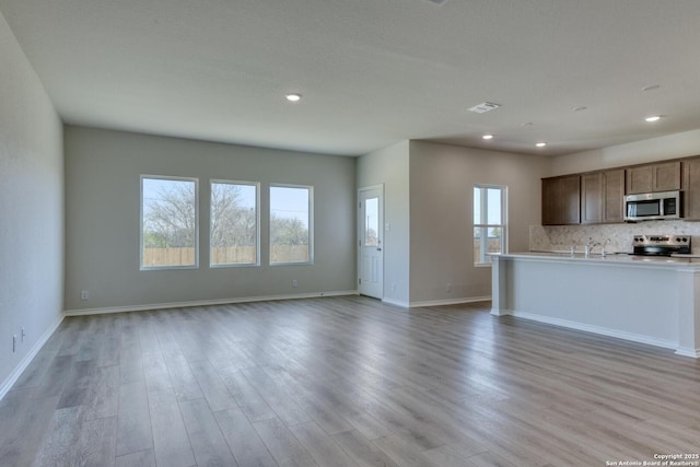 kitchen featuring decorative backsplash, appliances with stainless steel finishes, and light wood-type flooring