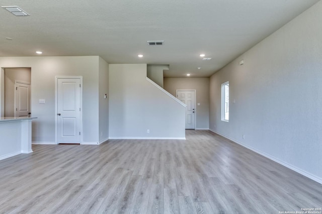 empty room featuring a textured ceiling and light hardwood / wood-style floors