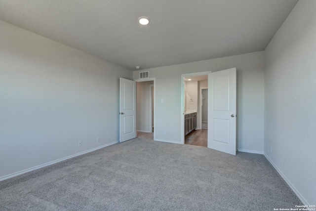 unfurnished bedroom featuring light carpet and ensuite bath