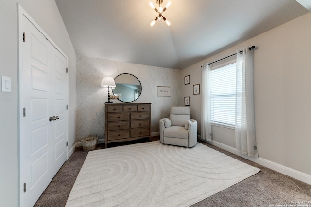 sitting room with a chandelier, lofted ceiling, and dark colored carpet