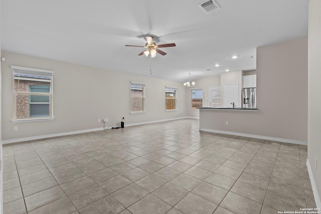 unfurnished room with light tile patterned floors, ceiling fan with notable chandelier, and sink